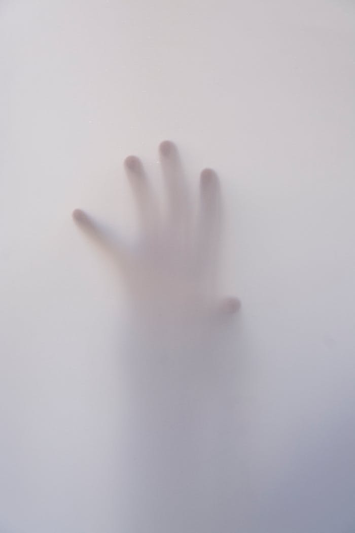Eerie image of a hand reaching through a foggy surface, evoking mystery and suspense.